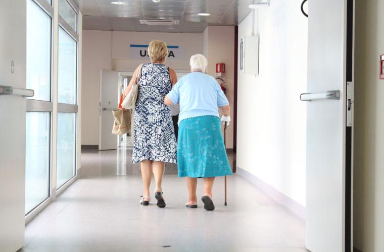 Two elderly ladies walking down a hospital corridor