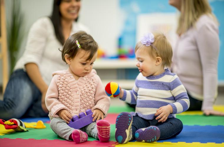 Babies playing in a soft play area with two women behind them