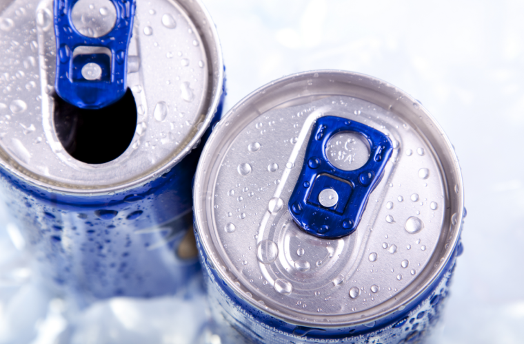 Two blue and silver energy drinks cans with condensation water droplets on the lid and blue pull rings.