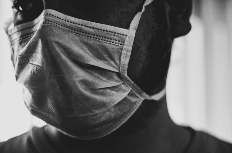A black and white photograph of a man wearing a face mask
