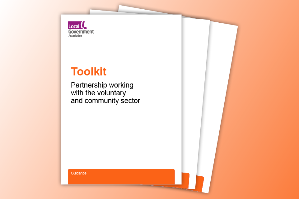 Orange background with three white document pages with text on the front page saying toolkit for partnership working with the voluntary and community sector
