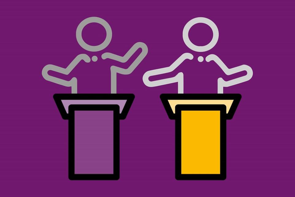 Two figures on a podium talking to an audience, magenta background